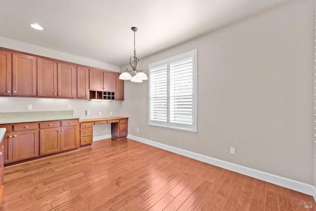 kitchen with baseboards, hanging light fixtures, open shelves, brown cabinets, and built in desk