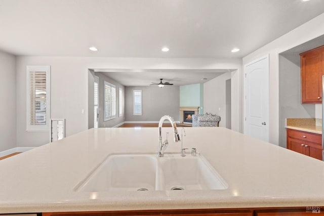 kitchen with a sink, a lit fireplace, open floor plan, light countertops, and recessed lighting