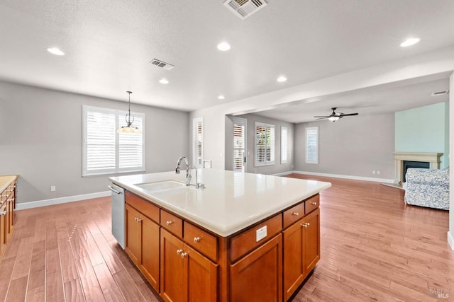 kitchen featuring brown cabinetry, baseboards, light wood-style flooring, and visible vents