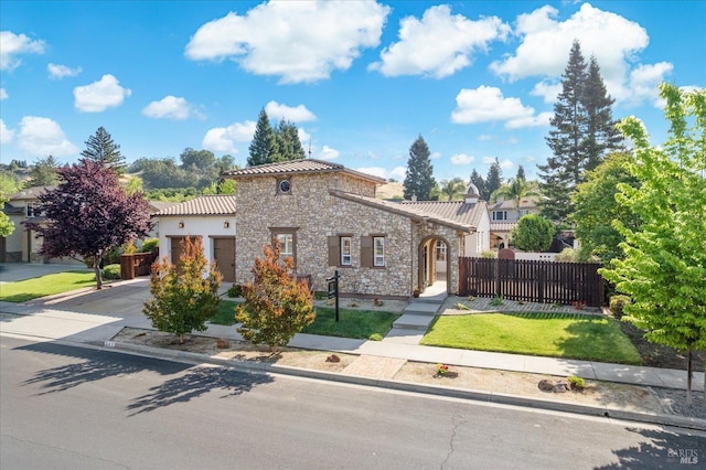 view of front facade with stone siding, a garage, fence, a front yard, and driveway