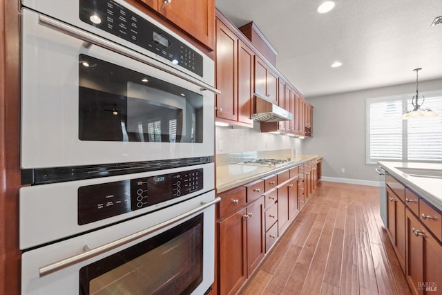kitchen with light countertops, light wood-style floors, stainless steel appliances, and baseboards
