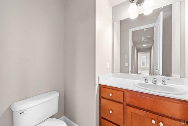 bathroom with toilet, vanity, and visible vents