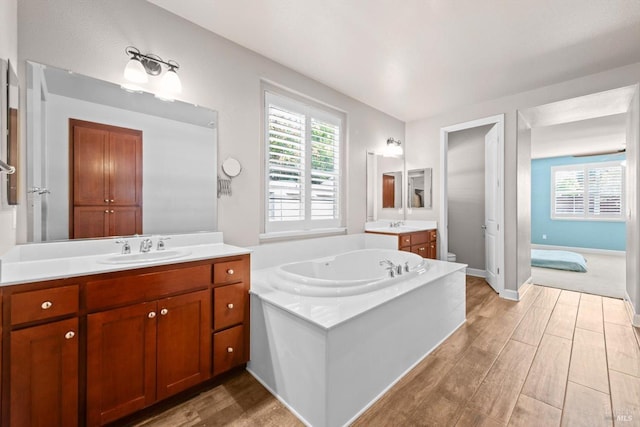 full bathroom with a wealth of natural light, wood finished floors, and a sink