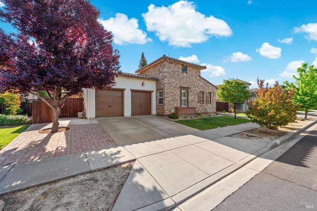 view of front of home featuring fence, an attached garage, stucco siding, concrete driveway, and stone siding