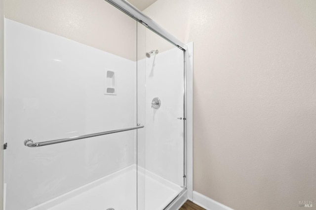 full bath with a shower stall and baseboards