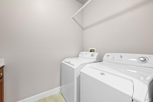 washroom with washing machine and clothes dryer, baseboards, and laundry area