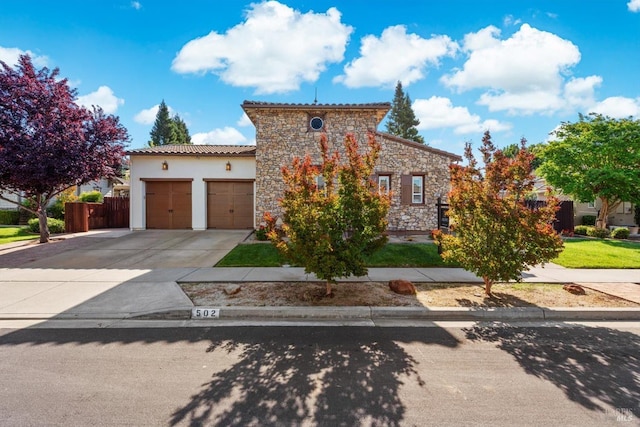 mediterranean / spanish-style home featuring driveway, a garage, stucco siding, a tile roof, and stone siding