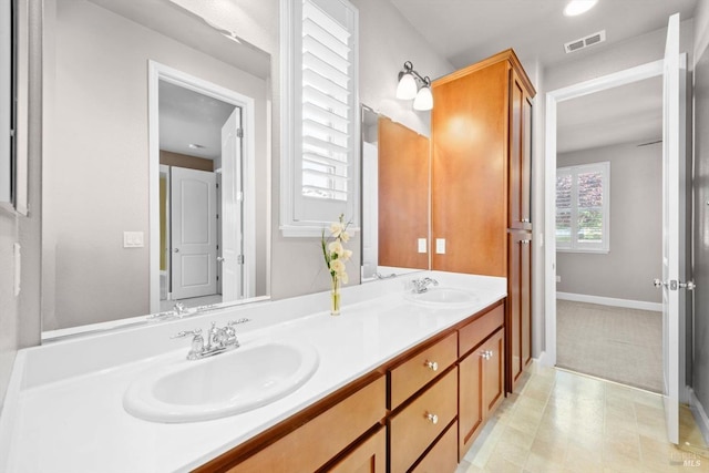 bathroom featuring baseboards, visible vents, a sink, and double vanity