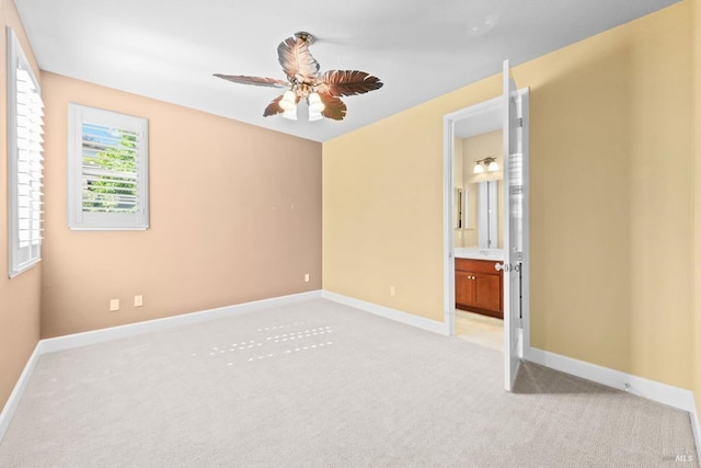 unfurnished bedroom with baseboards, ensuite bathroom, ceiling fan, and light colored carpet