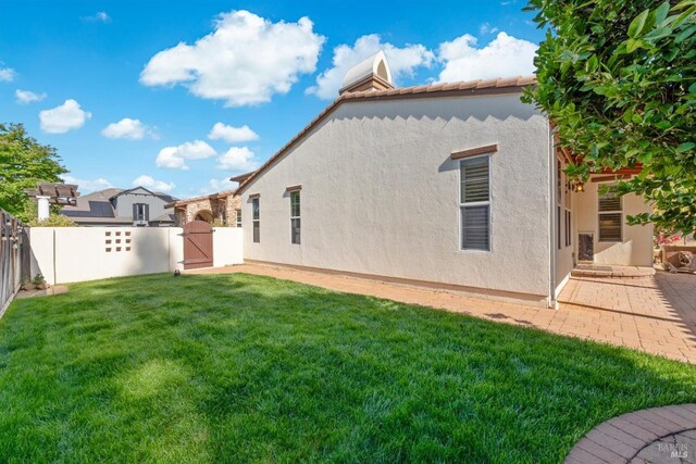 rear view of property with a yard, stucco siding, a fenced backyard, and a gate