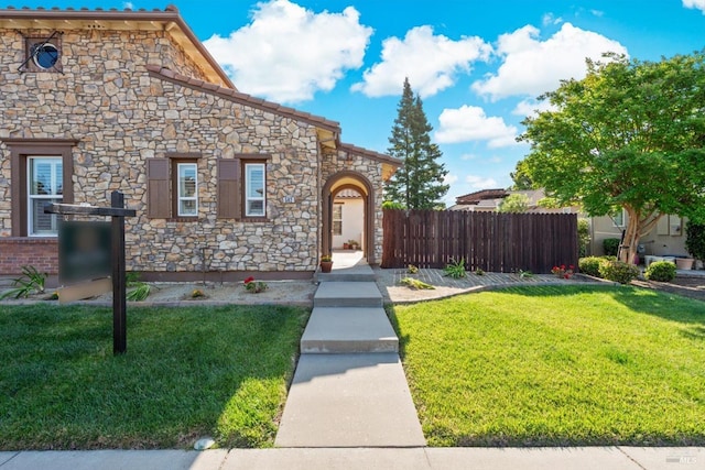 view of front facade with a front lawn, fence, and stone siding