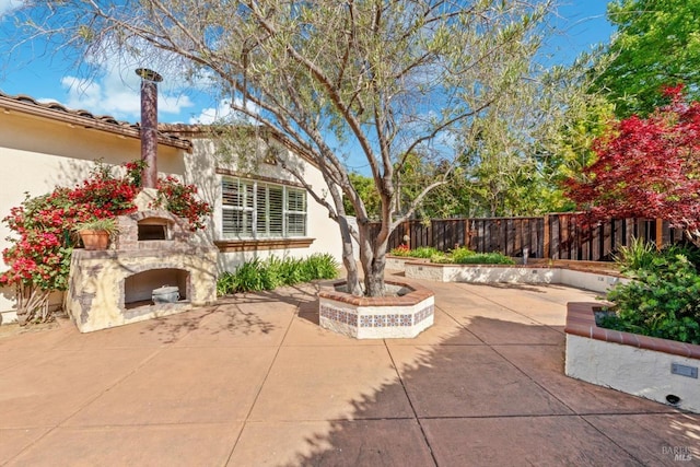view of patio with a fenced backyard and an outdoor stone fireplace