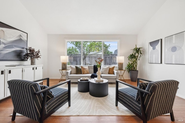 living area with wood finished floors, baseboards, and lofted ceiling