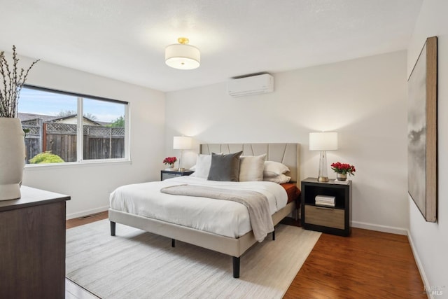 bedroom with an AC wall unit, baseboards, visible vents, and wood finished floors