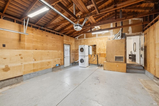garage with a garage door opener and stacked washer / drying machine