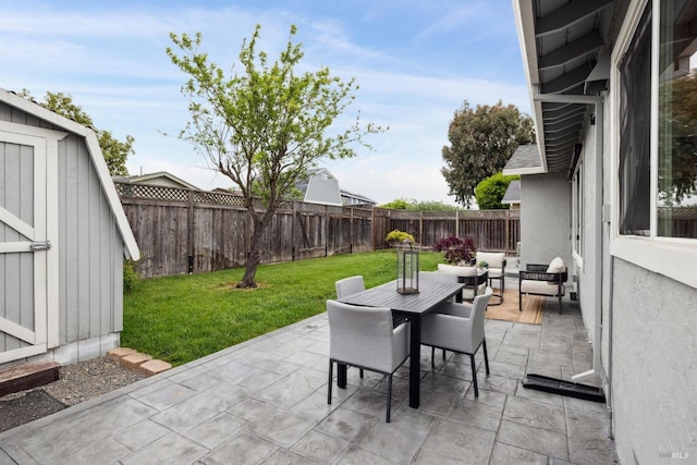 view of patio featuring an outdoor structure, a fenced backyard, a storage shed, and outdoor dining space