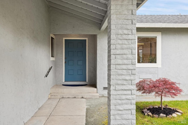 doorway to property with a chimney, a shingled roof, and stucco siding