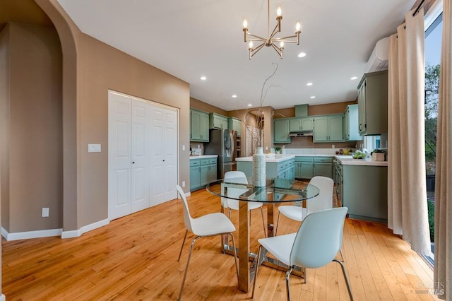 dining space with baseboards, recessed lighting, a chandelier, arched walkways, and light wood-style flooring