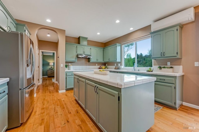 kitchen with stainless steel refrigerator with ice dispenser, green cabinetry, and an AC wall unit