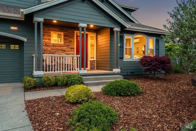 exterior entry at dusk featuring a garage and covered porch