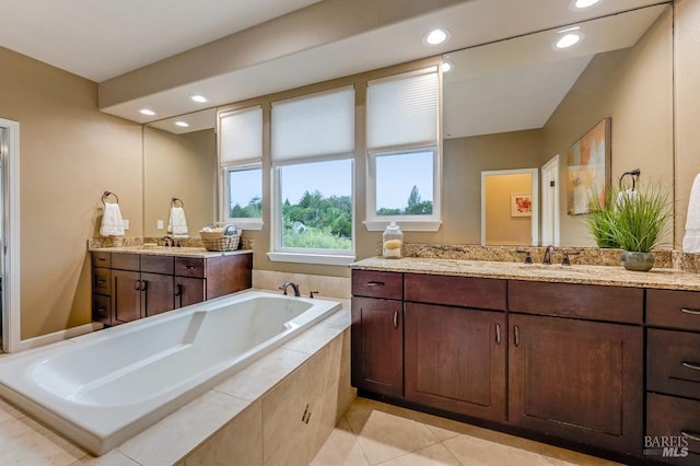 bathroom featuring tile patterned flooring, recessed lighting, a bath, and two vanities