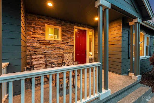 view of exterior entry featuring a porch and stone siding