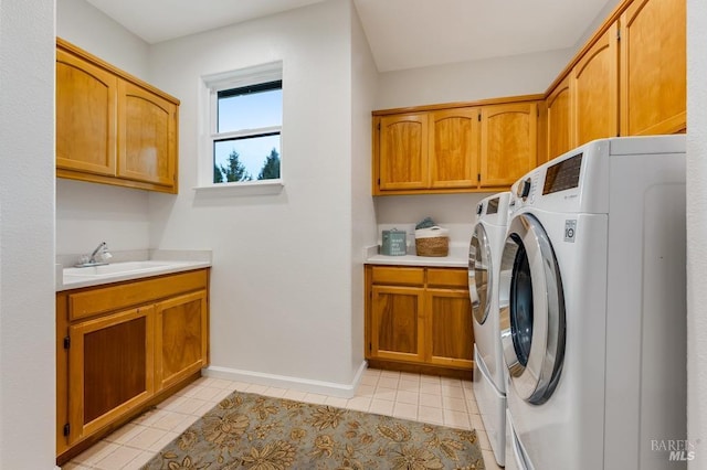 clothes washing area featuring washing machine and dryer, cabinet space, a sink, light tile patterned floors, and baseboards