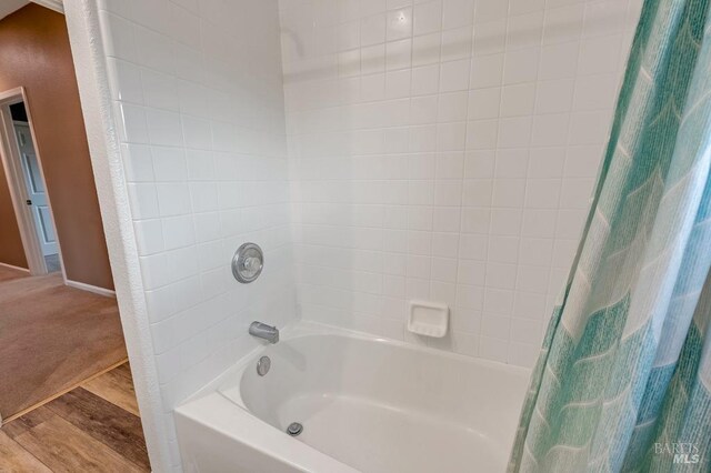 bathroom featuring wood finished floors and shower / tub combo with curtain