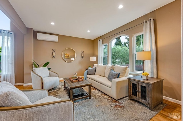 living room featuring an AC wall unit, baseboards, recessed lighting, and wood finished floors