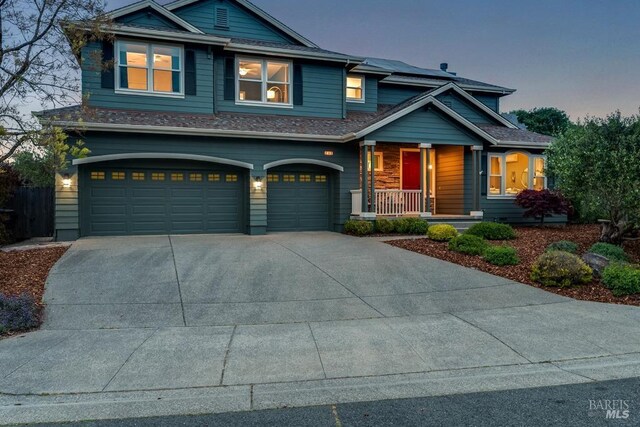 craftsman-style home featuring covered porch, concrete driveway, and a garage