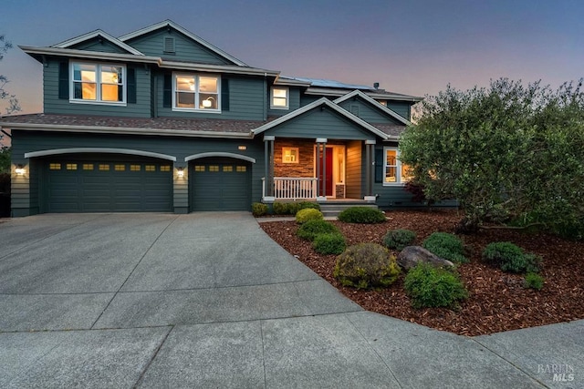 craftsman house with a porch, driveway, solar panels, and a garage