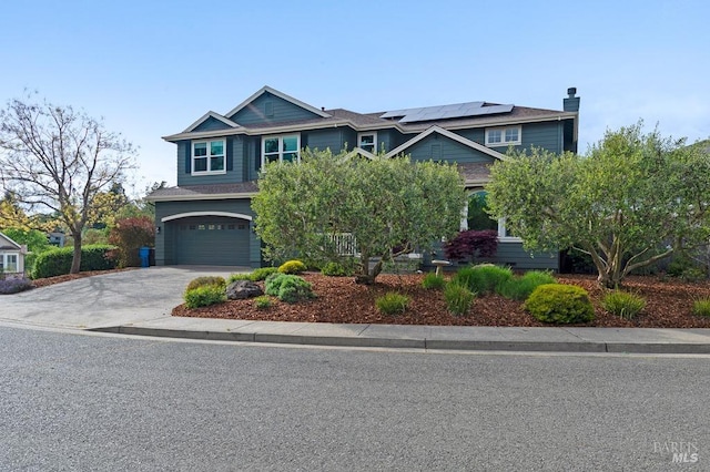 craftsman inspired home featuring concrete driveway, a chimney, roof mounted solar panels, and a garage