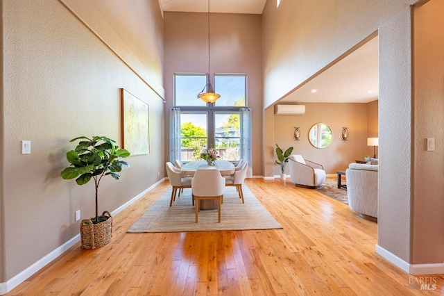 dining space with baseboards, a wall mounted AC, and hardwood / wood-style floors