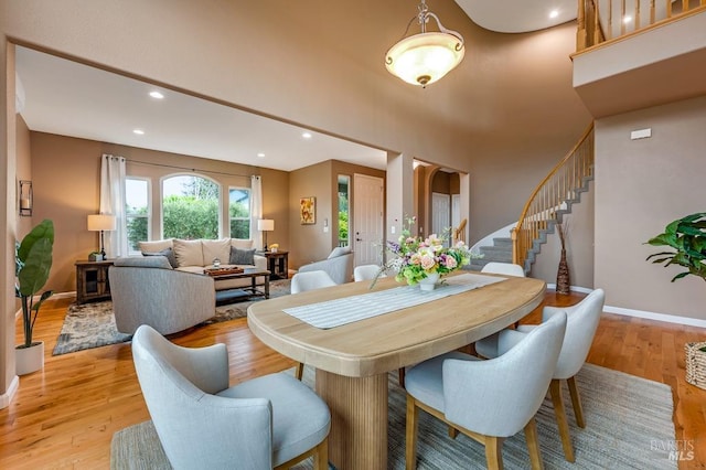 dining area with stairs, baseboards, a high ceiling, recessed lighting, and light wood-style flooring