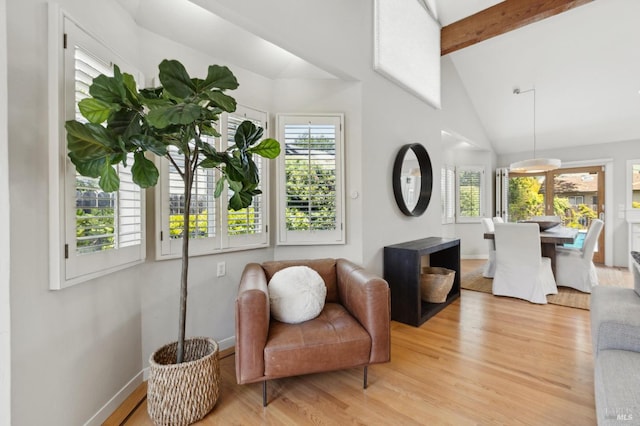 living area with vaulted ceiling with beams, baseboards, and light wood-type flooring