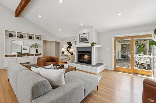 living room featuring light wood-style floors, baseboards, lofted ceiling with beams, a glass covered fireplace, and recessed lighting