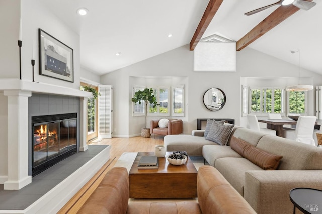 living area with a healthy amount of sunlight, baseboards, beam ceiling, and a tile fireplace