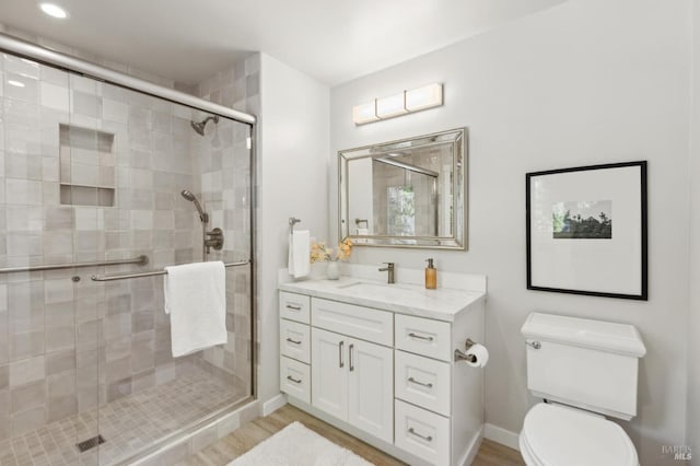 bathroom featuring toilet, wood finished floors, and a stall shower