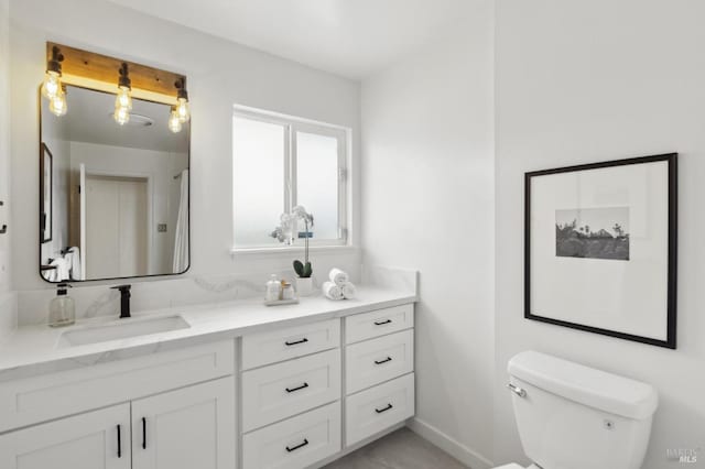 bathroom featuring vanity, baseboards, and toilet