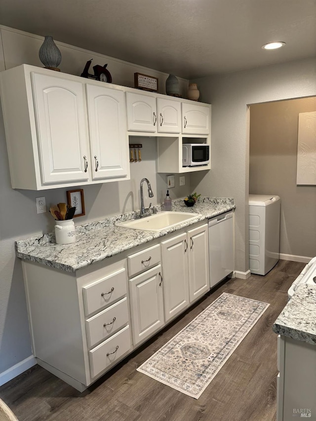 kitchen featuring a sink, dishwasher, washer / clothes dryer, white cabinetry, and dark wood-style floors