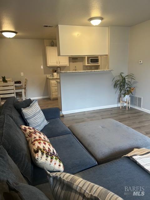 living room with baseboards, wood finished floors, and visible vents