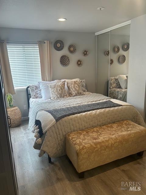 bedroom featuring recessed lighting, wood finished floors, and a closet