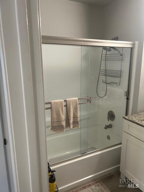 bathroom featuring combined bath / shower with glass door and vanity