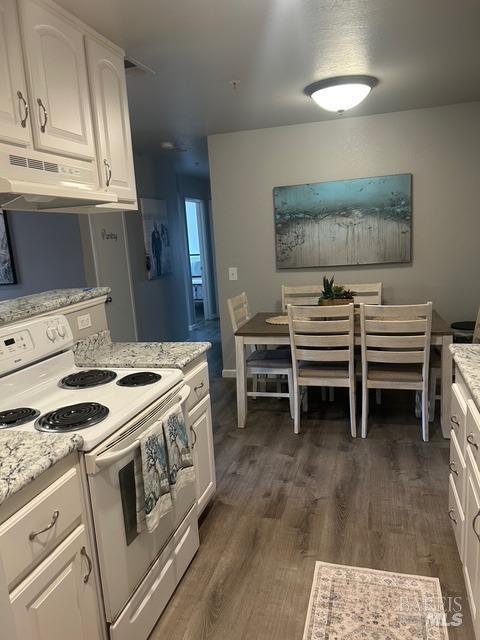 kitchen featuring under cabinet range hood, white range with electric cooktop, white cabinets, and dark wood-type flooring