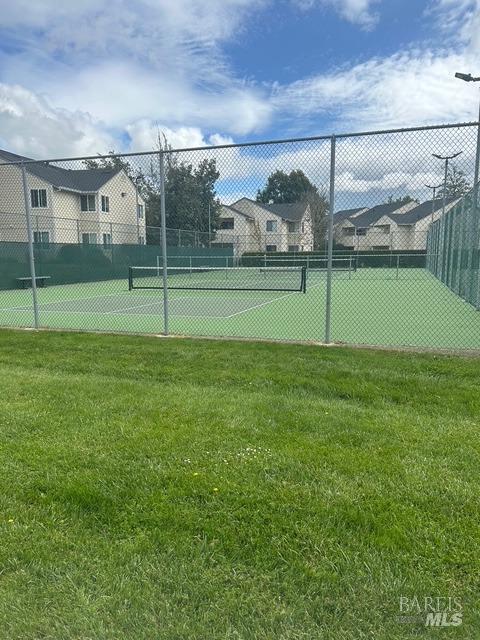 view of sport court with a lawn and fence
