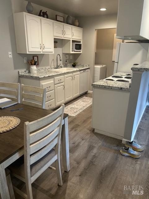 kitchen with washer and dryer, white cabinets, wall chimney exhaust hood, stainless steel appliances, and dark wood-style floors