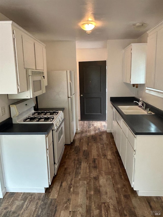 kitchen featuring dark countertops, a sink, white appliances, white cabinetry, and dark wood-type flooring