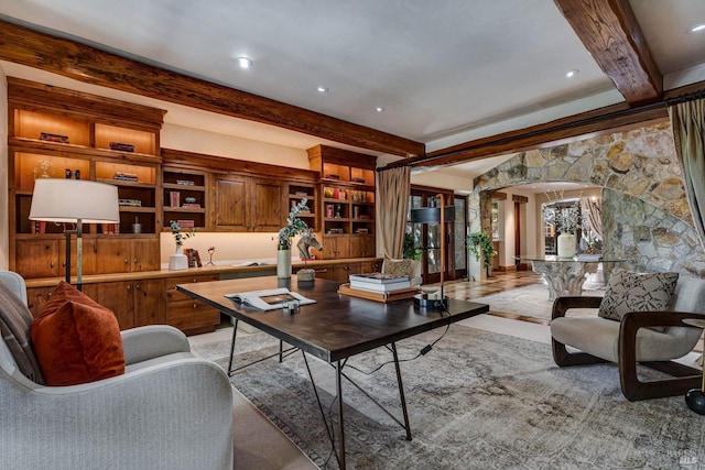 living area featuring arched walkways and beamed ceiling