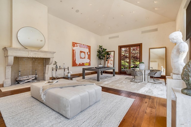 living area with high vaulted ceiling, hardwood / wood-style floors, and visible vents