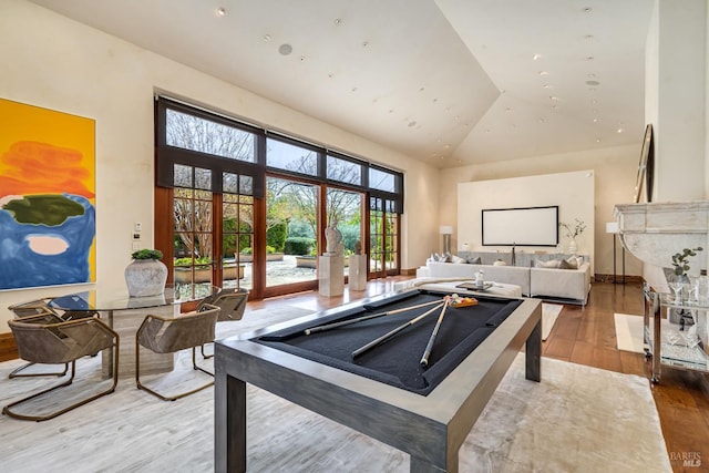 recreation room featuring wood finished floors and high vaulted ceiling